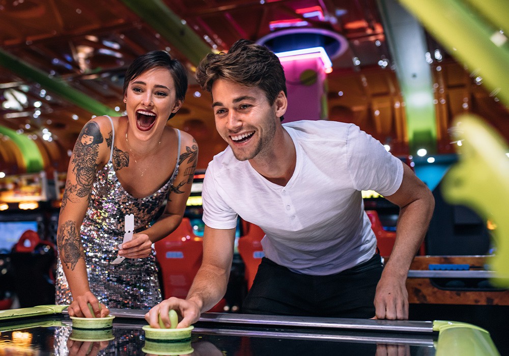 Island Social couple playing coin operated air hockey game